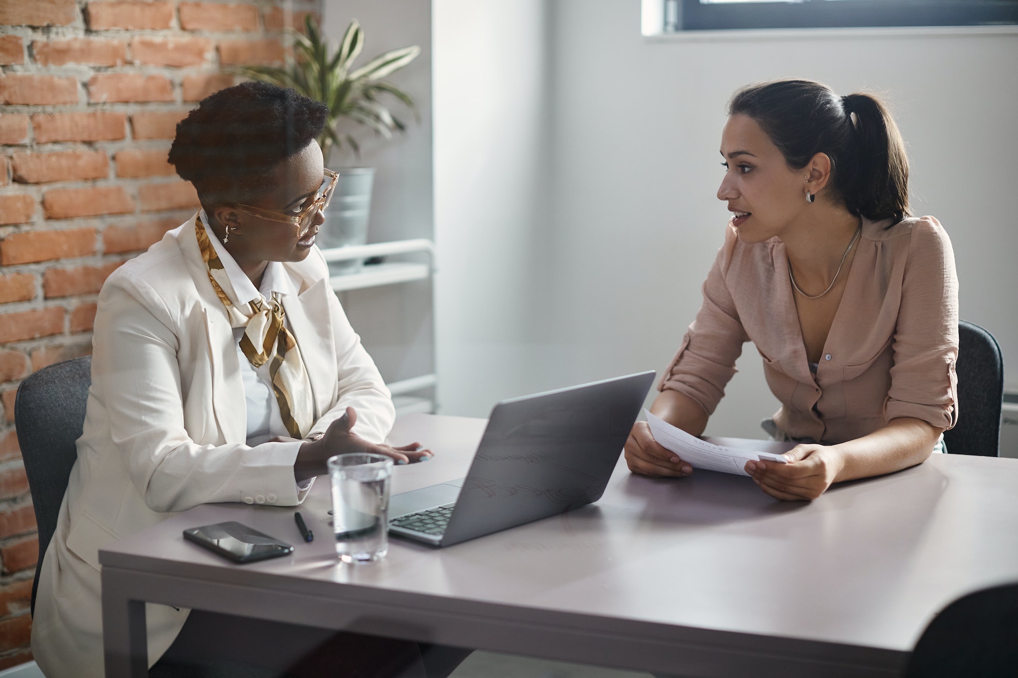 Female candidate talking to black businesswoman during job interview in the office.